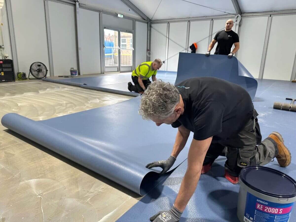 The team lay a vinyl roll at Ark Boulton's new portable classrooms.