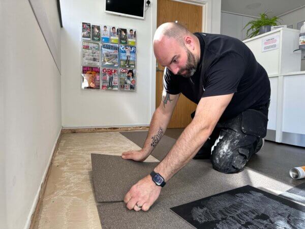 One of our fitters installing carpet tiles for a repair in the reception of a GP Clinic