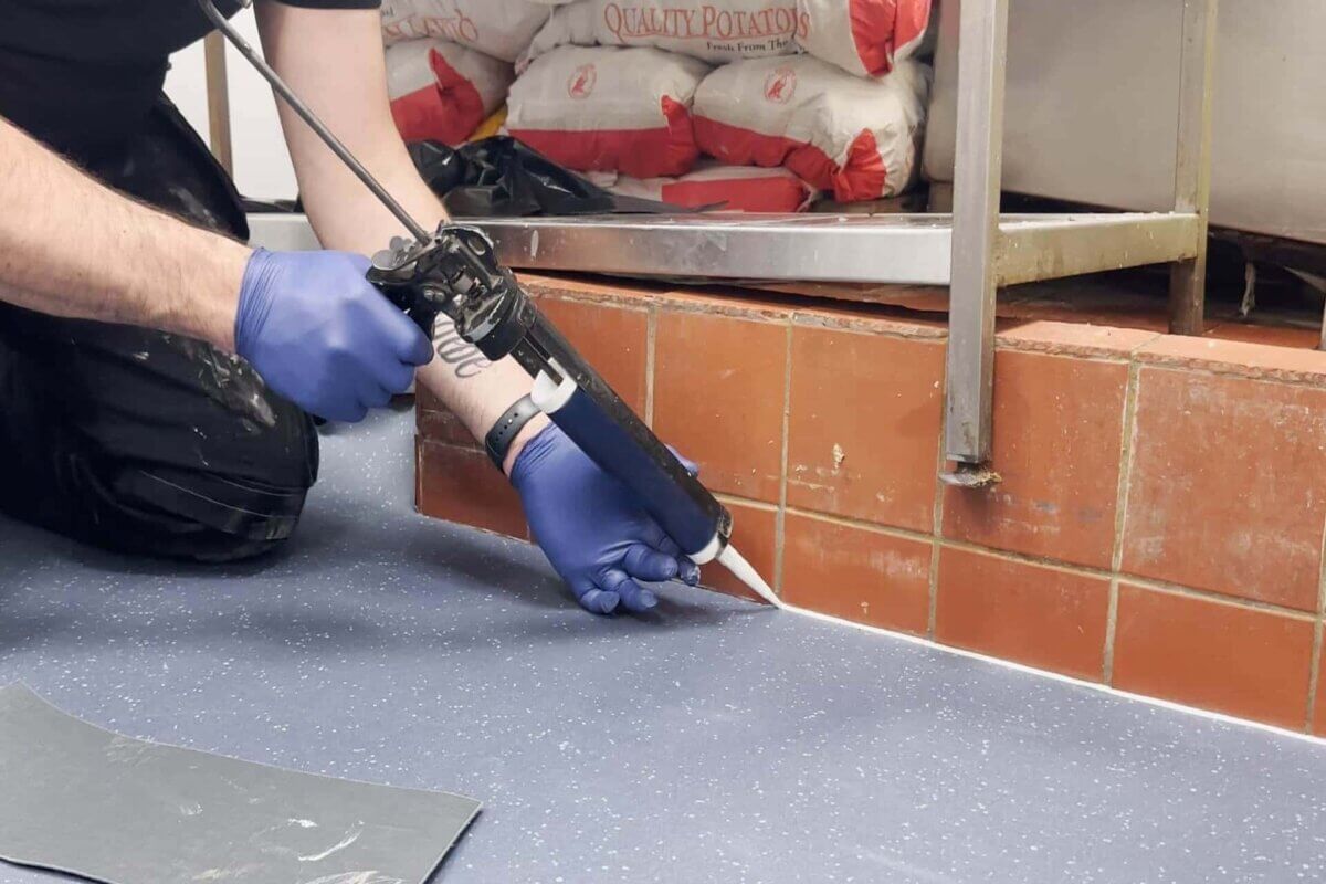 Applying glue to edges of safety vinyl at a Fish & Chip shop